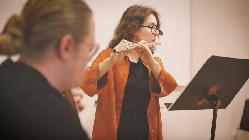 Two students playing flute and guitar together. Photo.