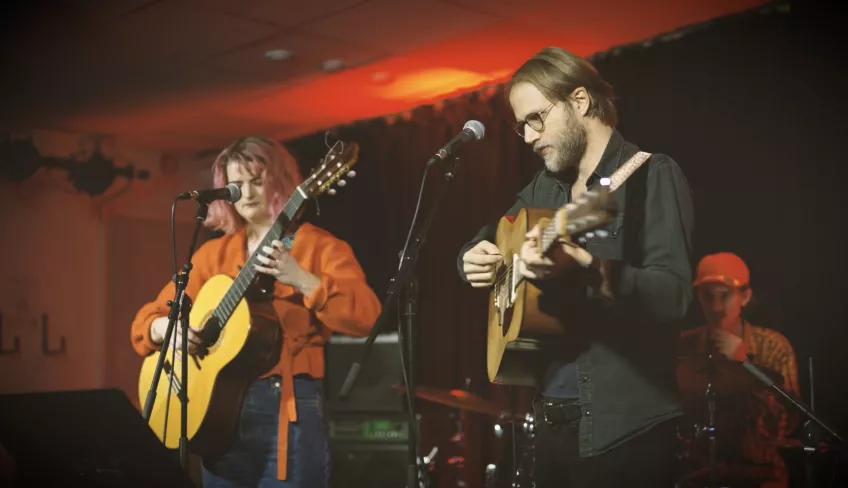 Two students playing guitar in a concert setting. Photo. 