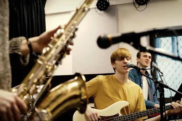 Tre studenter spelar musik tillsammmans. Foto. 