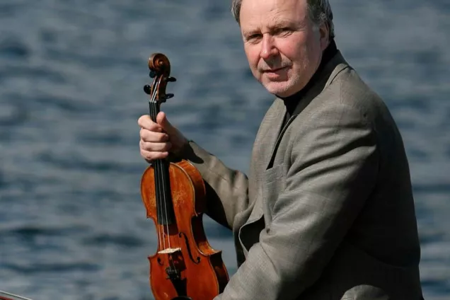 Terje Moe Hansen holsing his violin and looking into the camera. Photo.